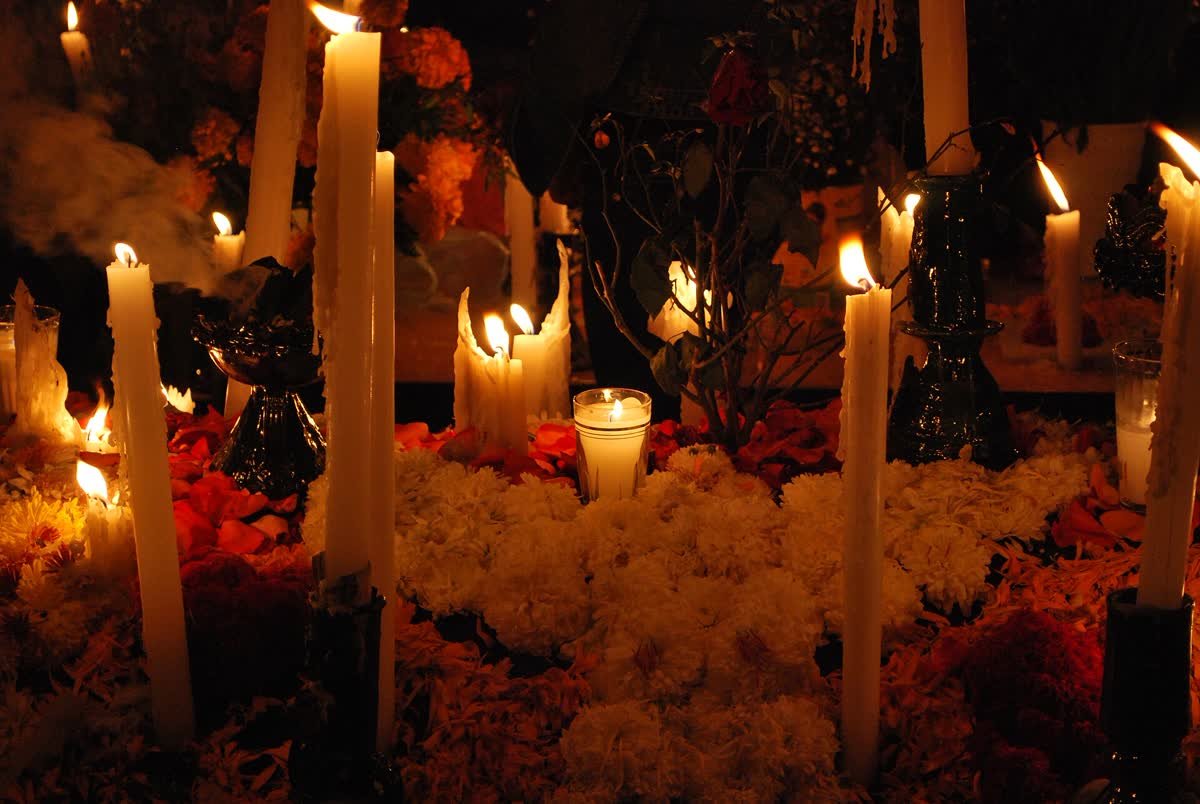 Candele accese e fiori di cempasúchil su un'ofrenda messicana, di notte.
